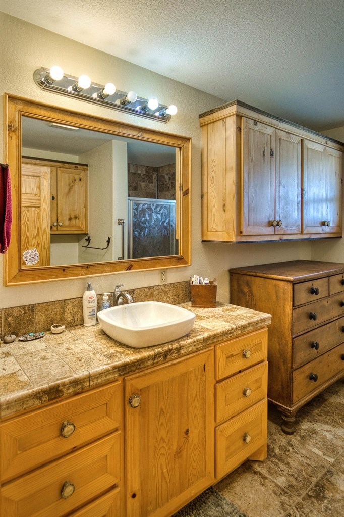 6446 Blackjack Road Fredonia, TX 76842 - Photo 23 of 48 a bathroom with a granite countertop sink and a mirror