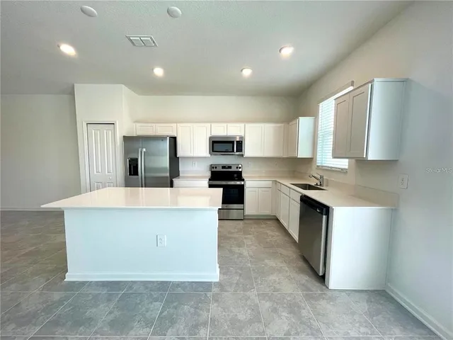 a large kitchen with a large counter top stainless steel appliances and cabinets