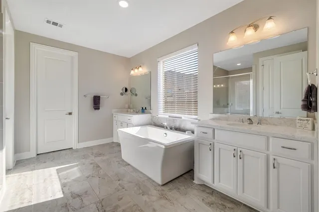 a spacious bathroom with a double vanity sink a mirror and a bathtub
