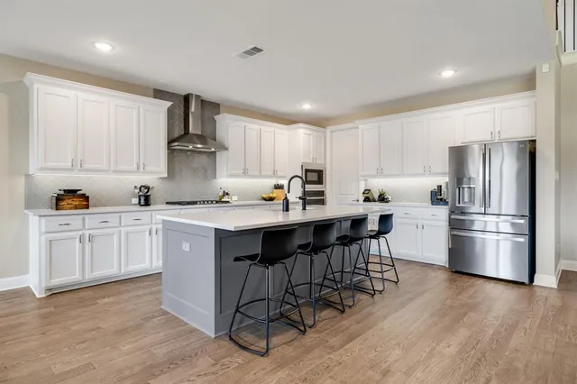 a kitchen with a refrigerator a sink dishwasher a stove and white cabinets with wooden floor