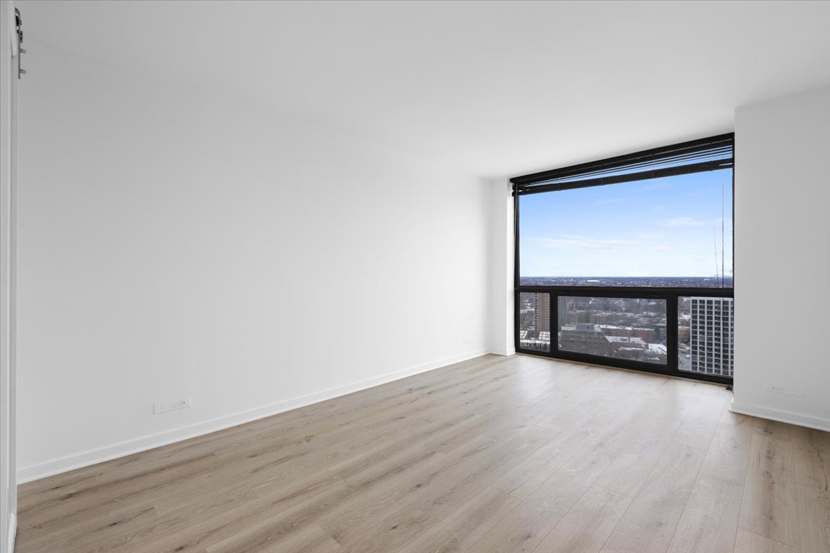 4343 North Clarendon Avenue, Unit 2507 Chicago, IL 60613 - Photo 17 of 23 a view of an empty room with wooden floor and a window