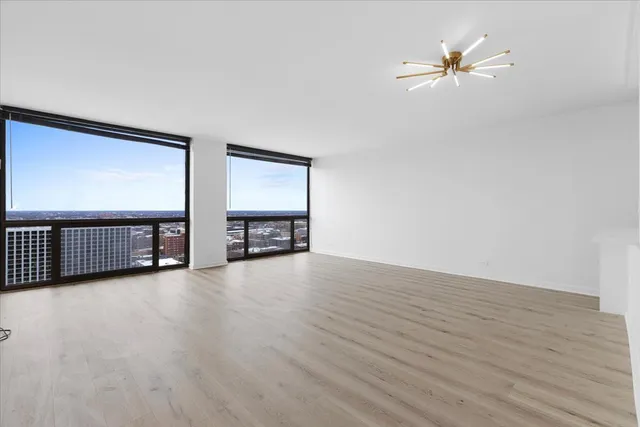 a view of a big room with wooden floor a ceiling fan and windows