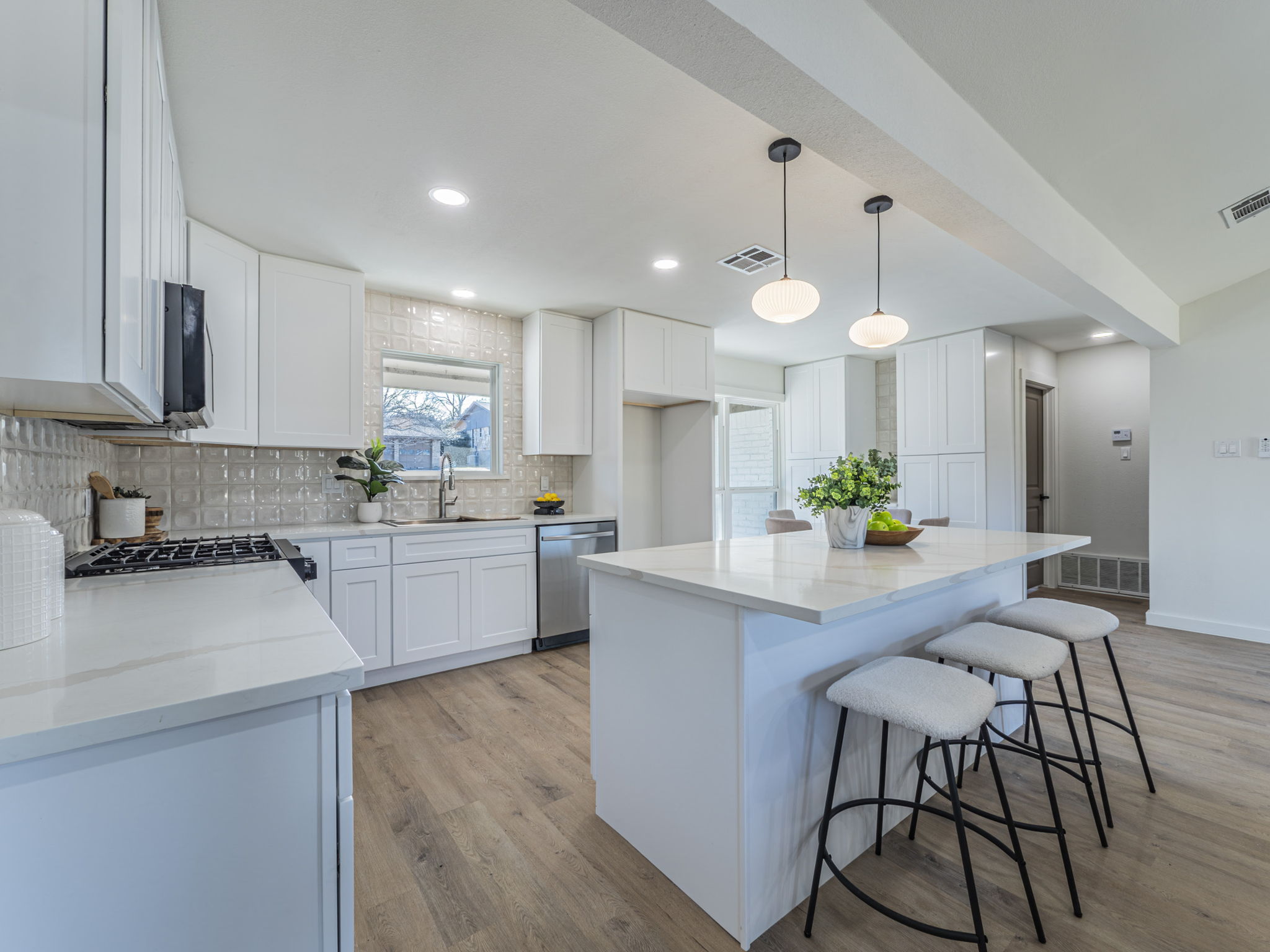 906 Fall Creek Drive Austin, TX 78753 - Photo 7 of 25 Kitchen with a breakfast bar, a center island, decorative light fixtures, light stone counters, and light wood-style floors