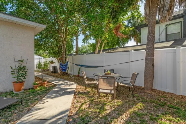 a view of a patio with table and chairs potted plants and large tree