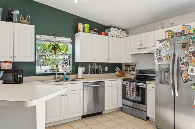 a kitchen with granite countertop a sink stainless steel appliances and white cabinets