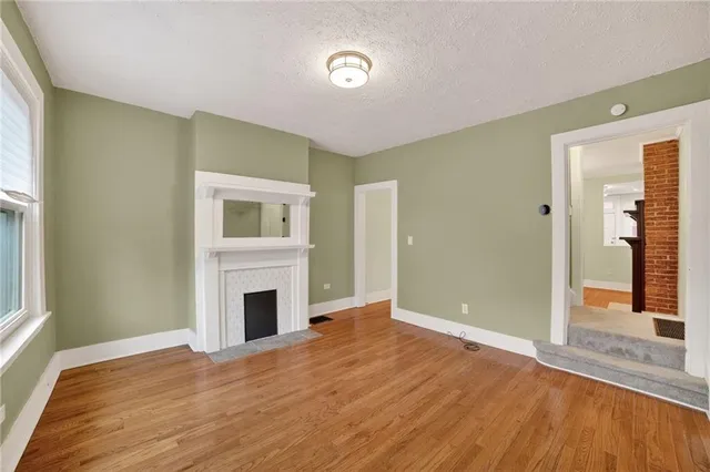 a view of empty room with wooden floor and fireplace