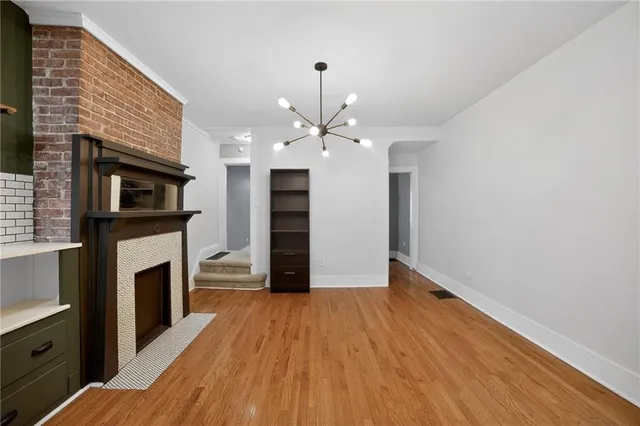 a view of a livingroom with a fireplace a chandelier and wooden floor