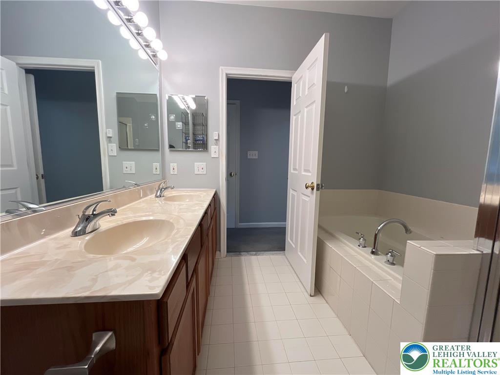 4224 Creek Road Allentown, PA 18104 - Photo 13 of 17 a bathroom with a granite countertop sink a bathtub a mirror and vanity