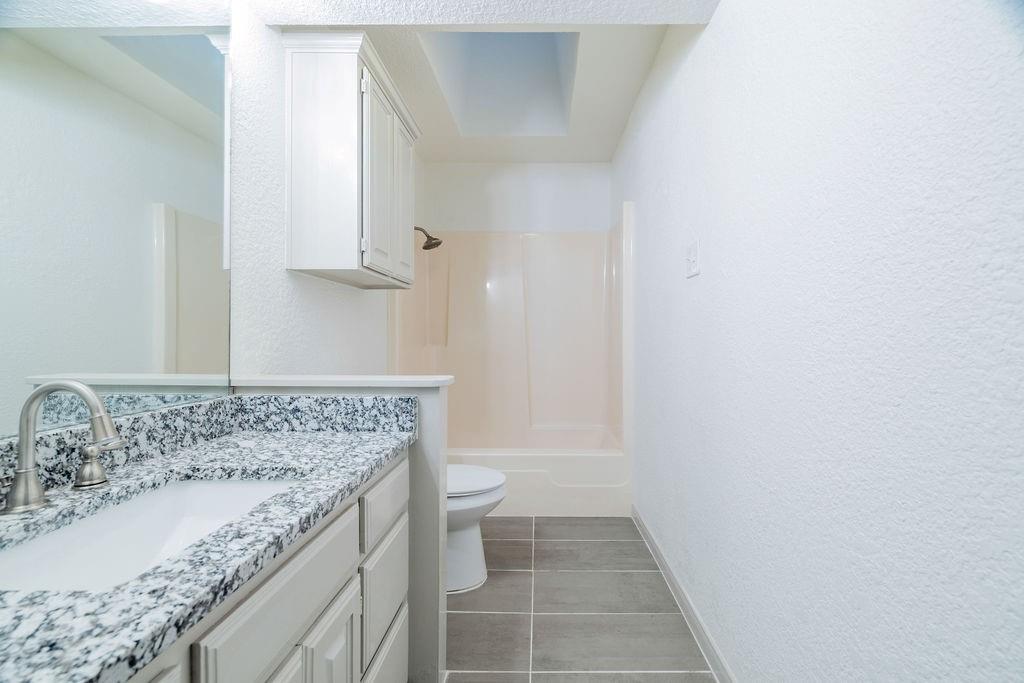 598 Stagecoach Trail Denison, TX 75021 - Photo 19 of 29 a bathroom with a granite countertop sink and a toilet