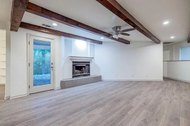 an empty room with wooden floor a ceiling fan and windows