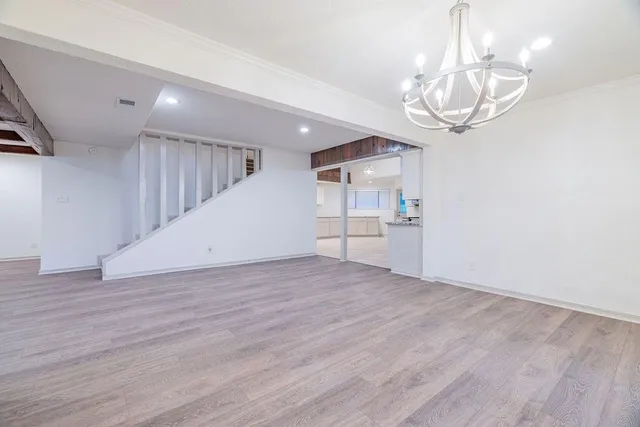 a view of empty room with wooden floor and chandelier