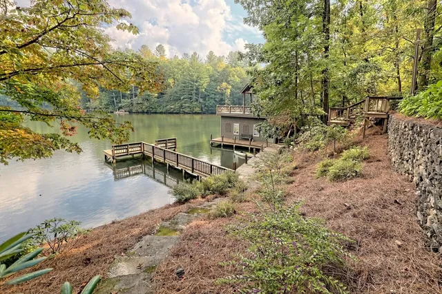 a view of a lake with a bench and trees in the background