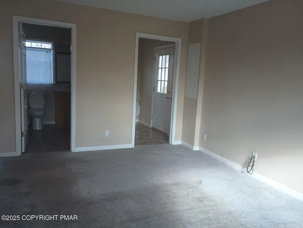 a view of an empty room with closet and mirror