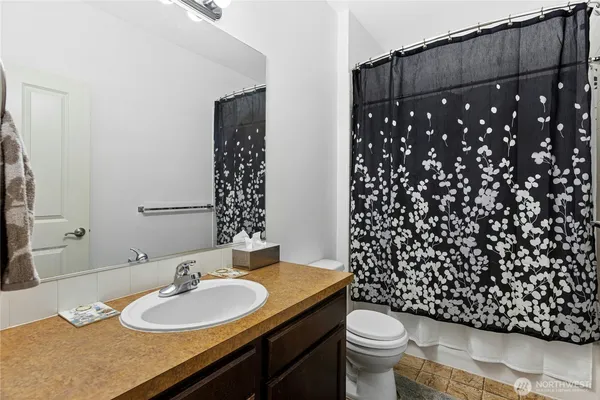 a bathroom with a sink a toilet a mirror and shower curtain