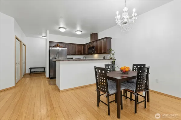 a kitchen with stainless steel appliances a table chairs refrigerator and a wooden floor