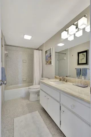 a bathroom with a granite countertop sink mirror bathtub and toilet