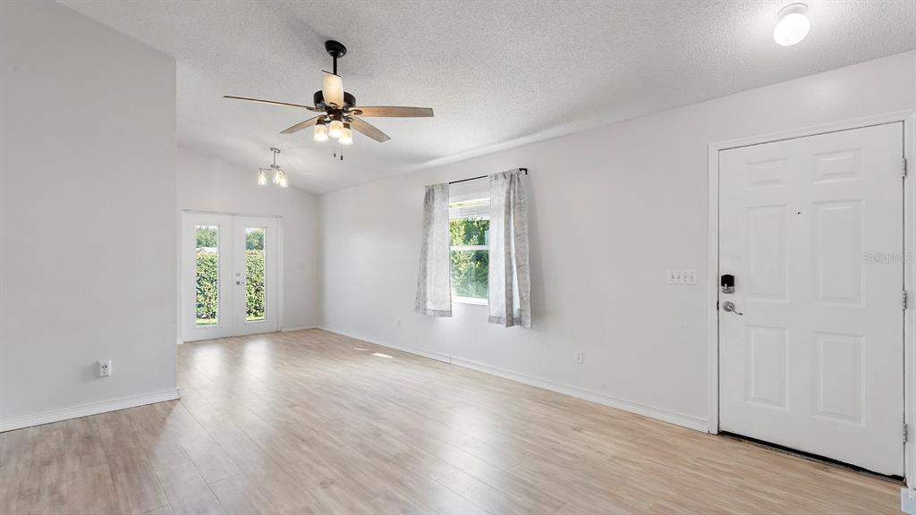 11029 Einbender Road Orlando, FL 32825 - Photo 3 of 27 an empty room with wooden floor chandelier fan and windows
