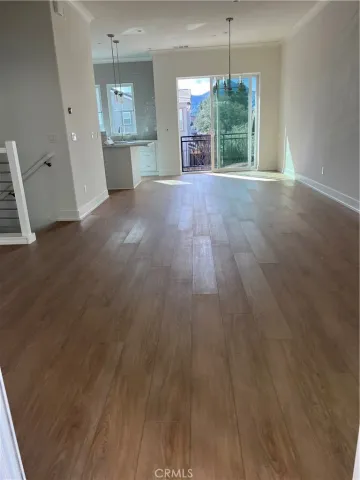a view of a room with wooden floor kitchen view and windows