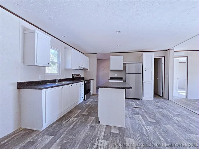 a kitchen with granite countertop a refrigerator and a stove top oven