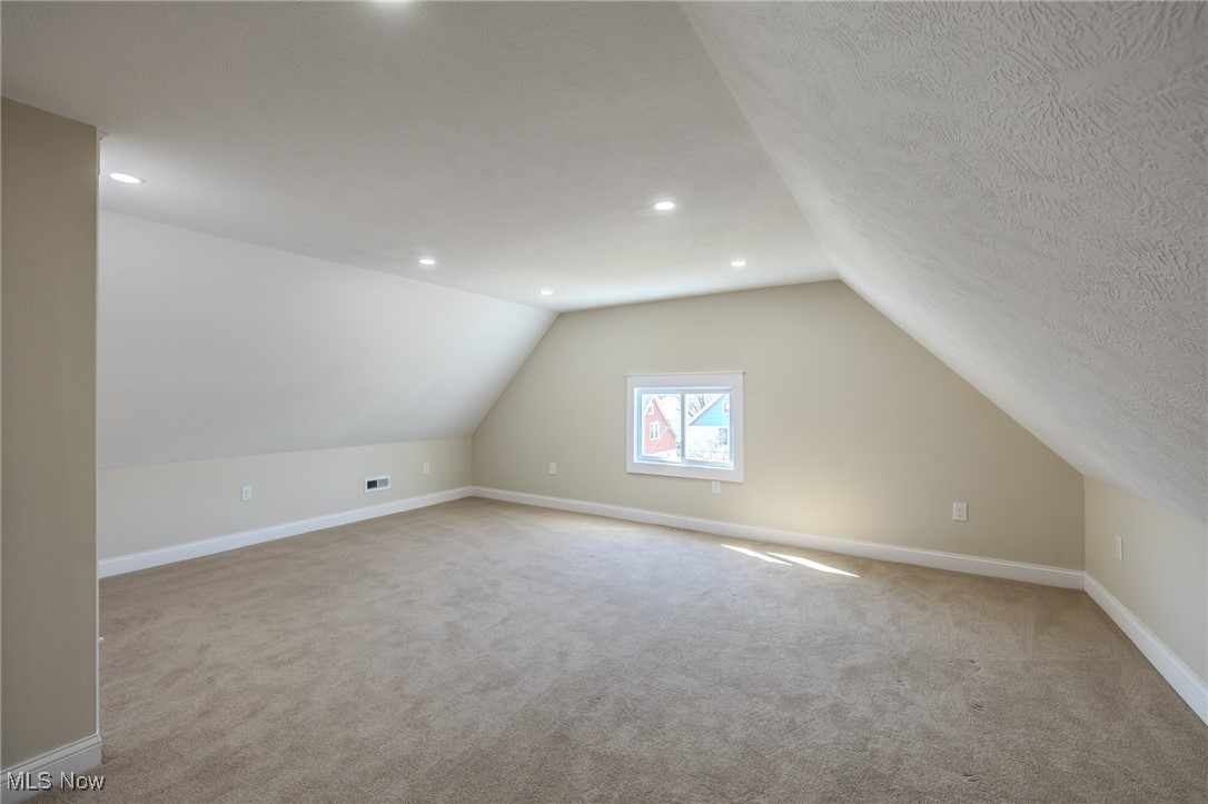 3516 Broadview Road Cleveland, OH 44109 - Photo 38 of 42 Additional living space with visible vents, carpet, baseboards, vaulted ceiling, and a textured ceiling