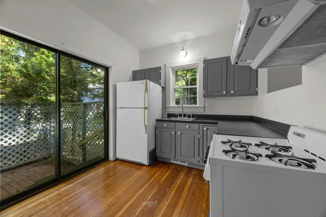 a kitchen with a stove a refrigerator and a wooden floor