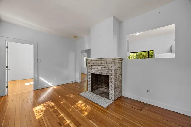 a living room with wooden floor and a fireplace