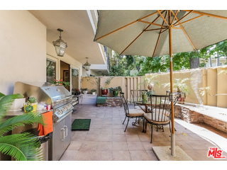 281 South Barrington Avenue, Unit C2 Los Angeles, CA 90049 - Photo 17 of 24 a view of a patio with a table and chairs under an umbrella