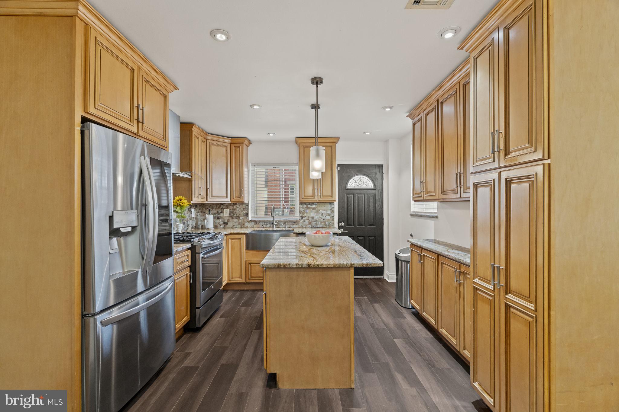 a kitchen with stainless steel appliances granite countertop a refrigerator a stove and a wooden floors