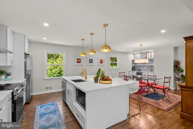 a kitchen with stainless steel appliances granite countertop a sink a stove and a wooden floors