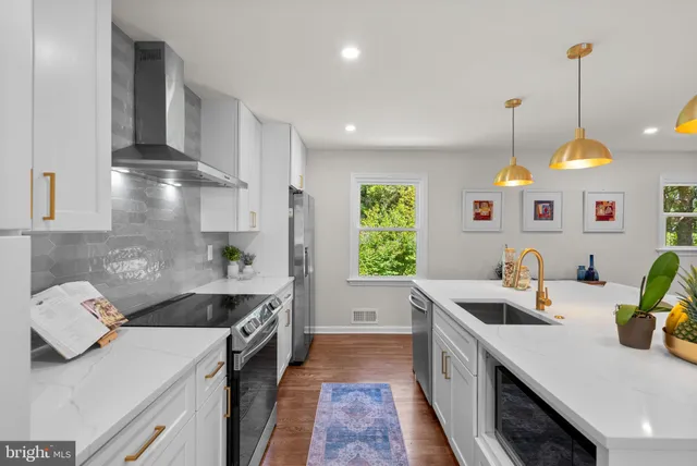 a kitchen with stainless steel appliances granite countertop a stove and white cabinets with wooden floor