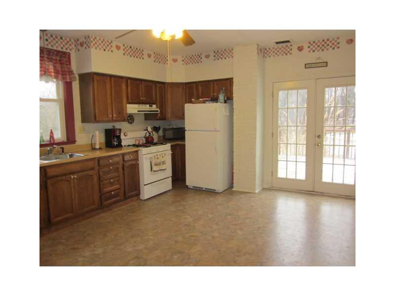 Kitchen. Generous eat-in kitchen with lovely oak cabinetry and butcher block style countertop, updated appliances, french doors that lead to a deck overlooking the large back yard & woods!