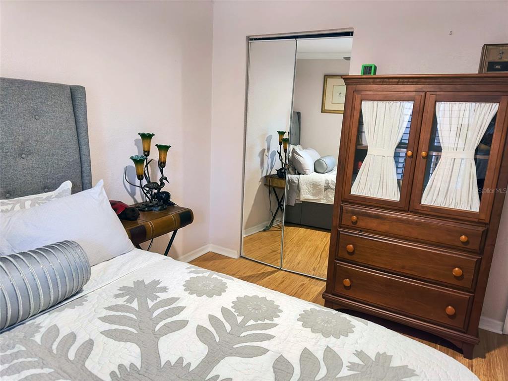 8911 Blind Pass Road, Unit 220 St. Pete Beach, FL 33706 - Photo 39 of 67 a bedroom with a bed and wooden floor