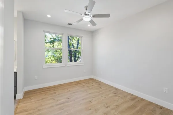 an empty room with windows and fan