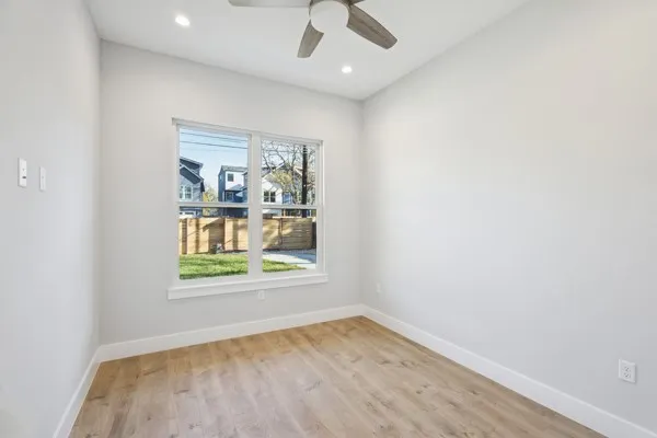 an empty room with a window and ceiling fan