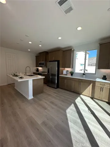 a large kitchen with stainless steel appliances kitchen island a large counter top a sink a stove and a refrigerator