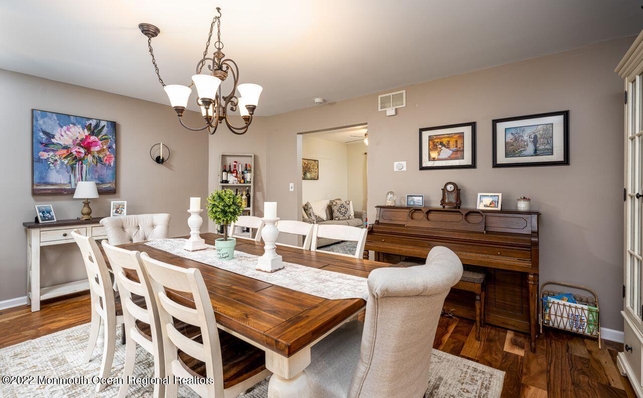 621 Reed Road Jackson, NJ 08527 - Photo 4 of 35 a dining room with wooden floor a chandelier a wooden table and chairs