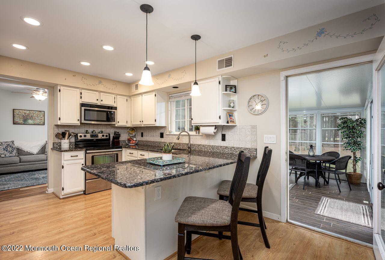 621 Reed Road Jackson, NJ 08527 - Photo 9 of 35 a kitchen with stainless steel appliances granite countertop a stove a sink dishwasher a dining table and chairs with wooden floor