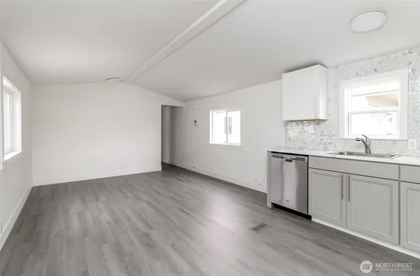 a kitchen with granite countertop a stove a sink and white cabinets with wooden floor