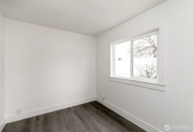 a kitchen with granite countertop a stove a sink and white cabinets with wooden floor