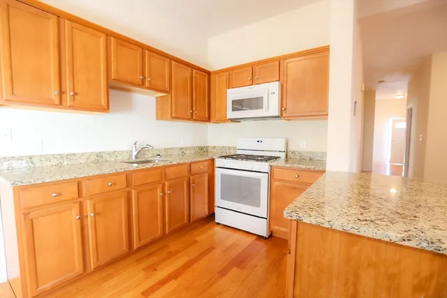a kitchen with granite countertop wooden cabinets and white appliances
