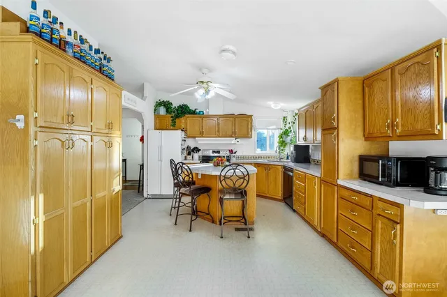 a kitchen with stainless steel appliances kitchen island granite countertop dining table chairs cabinets and a sink