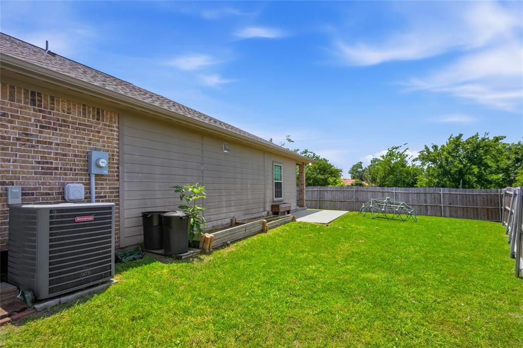 1502 Reed Street Greenville, TX 75401 - Photo 26 of 26 Expansive backyard featuring a lush green lawn, full privacy fencing, and a concrete patio pad