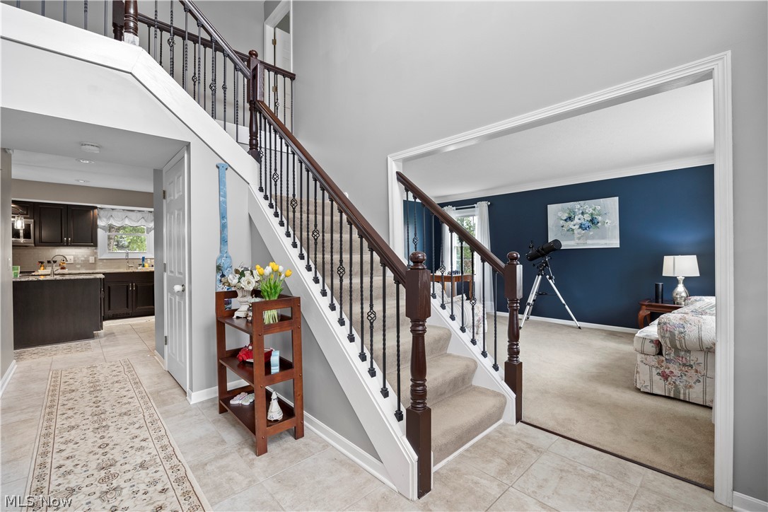 Two-story foyer with carpeted stairs and wrought iron balusters