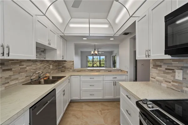 a kitchen with white cabinets and sink