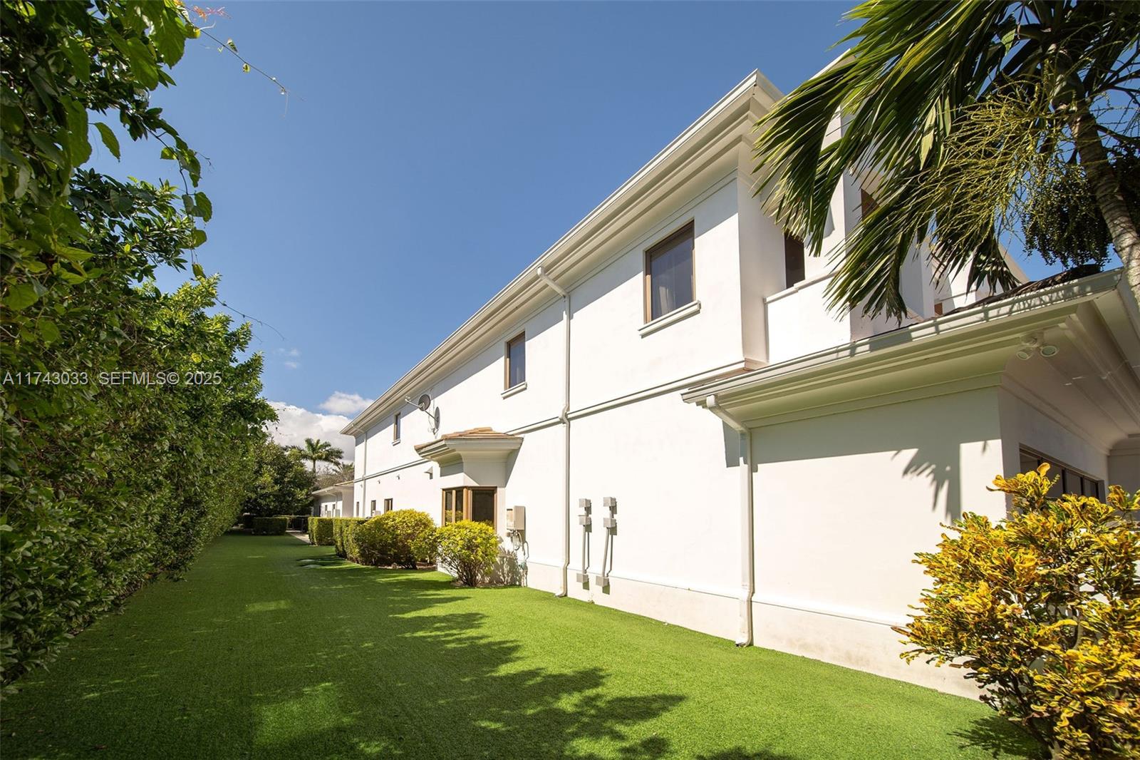8955 Southwest 63rd Court Pinecrest, FL 33156 - Photo 53 of 59 a view of a white house with a big yard and potted plants