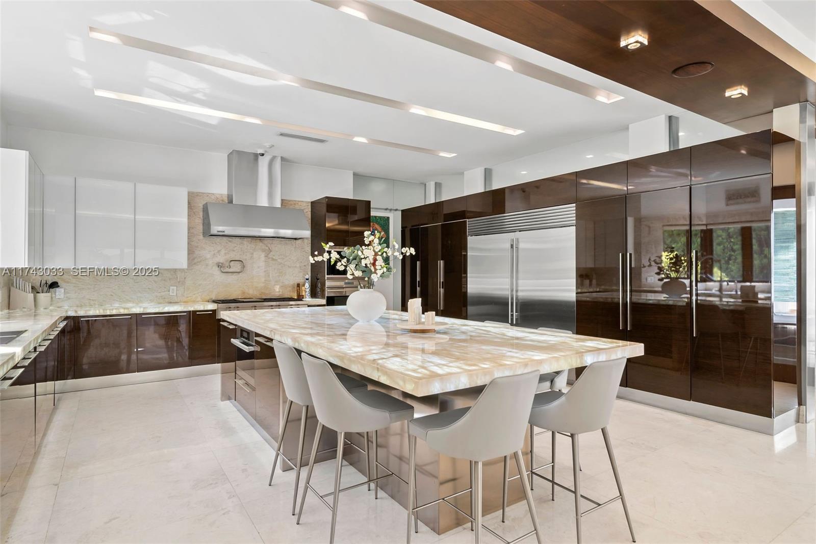 8955 Southwest 63rd Court Pinecrest, FL 33156 - Photo 7 of 59 a kitchen with stainless steel appliances kitchen island a table and chairs in it