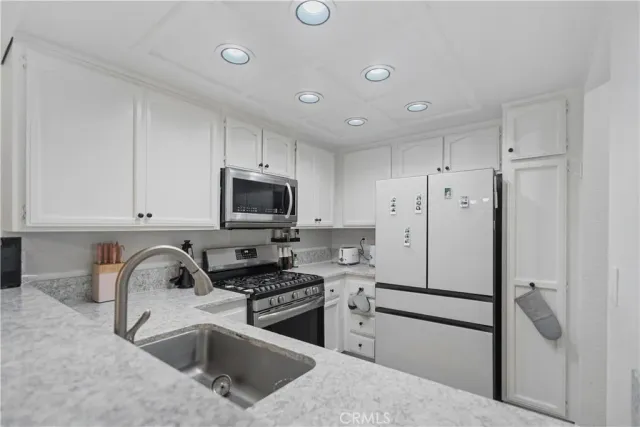 a kitchen with stainless steel appliances granite countertop a refrigerator sink and stove