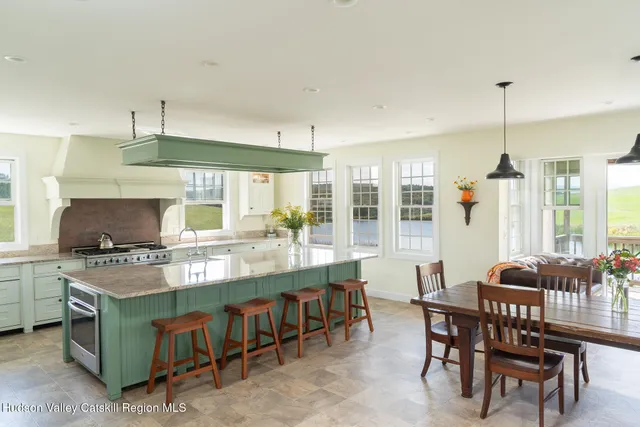 a kitchen with kitchen island granite countertop a stove a sink a dining table and chairs