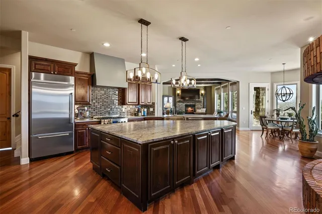 a kitchen with stainless steel appliances granite countertop a sink a stove and a wooden floors