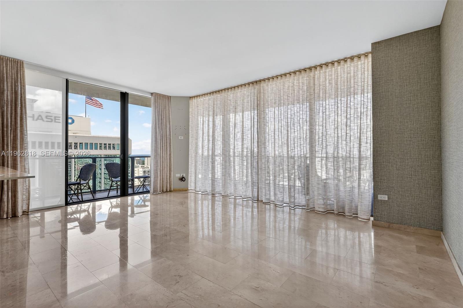 88 Southwest 7th Street, Unit 2402 Miami, FL 33130 - Photo 7 of 38 a view of an empty room with wooden floor and a window